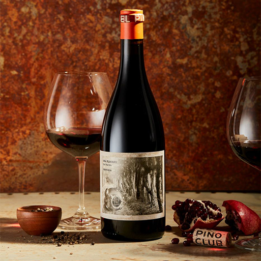 A bottle of El Pino Sea Floored wine on a table with two glasses of poured wine and some table decor
